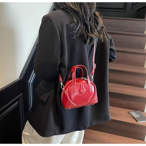 Detail of red heart-shaped leather bag with glossy finish and silver hardware details