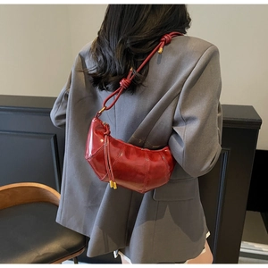 Detail of burgundy quilted leather crescent bag on shoulder with sleek metallic gold hardware
