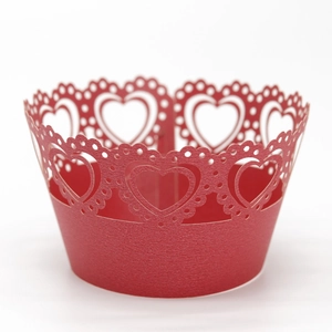 Close-up of laser-cut red heart pattern cupcake wrappers with detailed scalloped edges