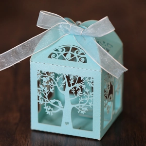 Detail of light blue laser-cut candy box with tree and bird patterns and silk ribbon