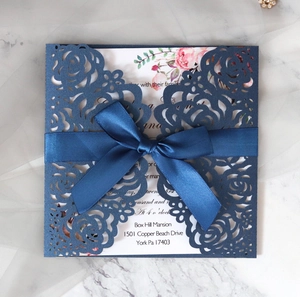 Detailed laser-cut rose wedding invitation with navy pearlescent cover and satin ribbon