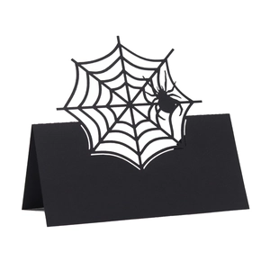 Detail of laser-cut spider web design on a black Halloween folding table place card