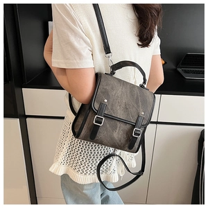 Detail of grey vintage canvas backpack with black leather straps and embossed metal buckles