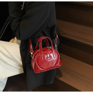 Detail view of red heart Boston bag with glossy leather texture and silver zipper
