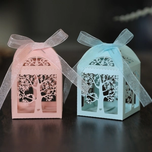 Close-up of laser-cut candy boxes with tree and bird patterns and organza bows