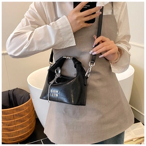 Detail view of black faux-crocodile leather bag with silver handles and metal chain