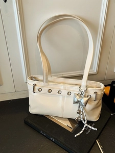 Borsa a spalla chic in PU beige con occhielli argentati e ciondolo a fiocco su libro