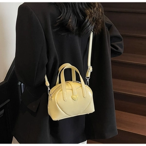 Macro detail of a pale yellow heart-shaped mini bag with quilted glossy leather texture