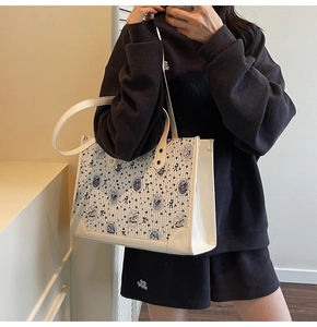 Détail latéral d'un sac cabas blanc avec imprimé ours et large bandoulière