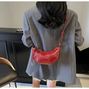 Detail of red dumpling bag with segmented stitching and glossy leather finish