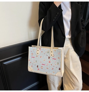Détail du sac cabas en tweed bleu clair avec motifs de dessins animés et anses en cuir