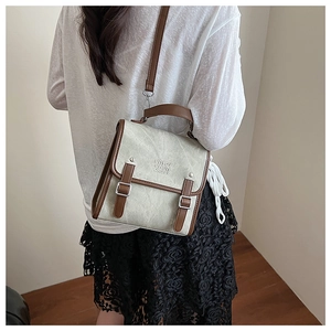 Detail view of canvas backpack featuring brown faux leather trim and embossed lettering