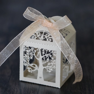 Detail showing laser-cut tree of life design on cream gift box with a pink organza bow