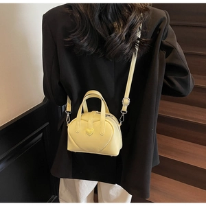 Chic yellow heart-shaped mini crossbody bag styled with a professional black blazer