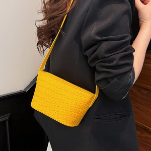 Close-up detail of the bright yellow woven leather texture on a minimalist crossbody bag