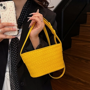 Detail of yellow woven leather handbag with intricate Intrecciato pattern and strap