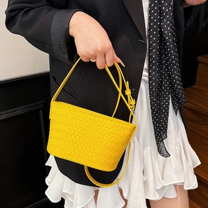 Detailed view of yellow woven leather small square handbag with adjustable strap