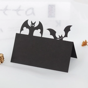 Close-up of laser-cut black paper bat place card for Halloween party table settings
