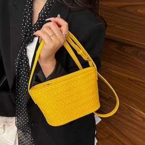 Detailed view of yellow woven square bag with adjustable strap held by a model