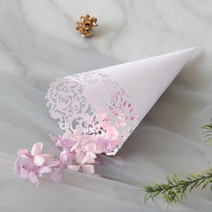 Detail of white laser-cut confetti cones with intricate floral lace and dried petals