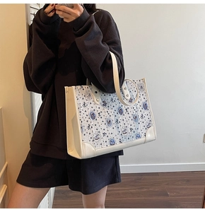 Grand sac cabas avec imprimés ours bleus et poignées en cuir blanc porté par un mannequin