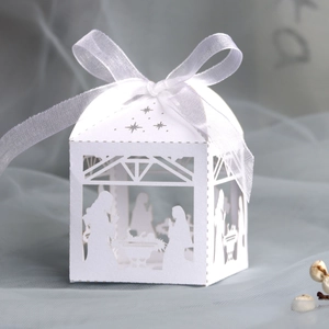 Detail of laser-cut white favor box featuring nativity scene and silk ribbon bow