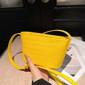 Detailed view of yellow woven leather texture on a stylish small square crossbody bag