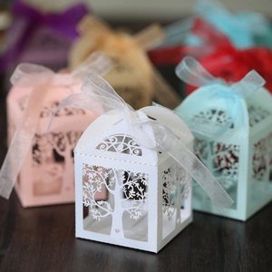 Detail of laser-cut candy boxes with intricate tree patterns and elegant ribbon bows