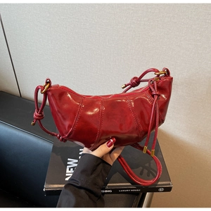 Detail of dark red dumpling bag with vertical quilting and drawstring knotted shoulder strap