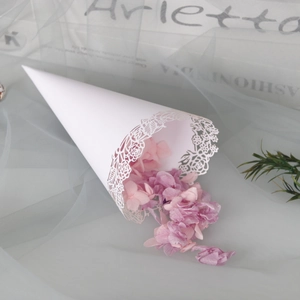 Detailed close-up of a white lace cutout paper cone filled with pink flower petals