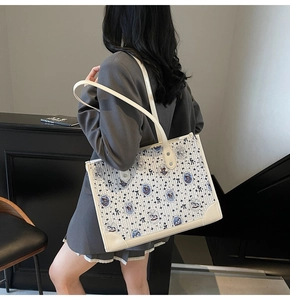 Gros plan du sac cabas avec motifs d'ours et bordures en cuir crème porté par un mannequin