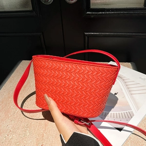 Detail of red woven leather crossbody bag showing intricate texture and adjustable strap