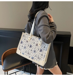 Détail du sac cabas crème avec imprimé ours bleu montrant le tissu et les anses en cuir