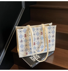 Détail d'un sac cabas crème avec imprimé ours et motifs bleus sur escalier bois