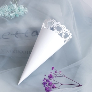 White laser-cut heart pattern wedding confetti cone on soft blue organza fabric background