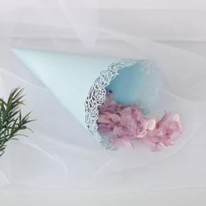 Close-up of light blue confetti cone with floral laser-cut edges and pink dried petals