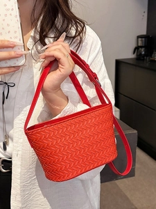 Classic red woven leather bucket bag with an adjustable strap shown on a model