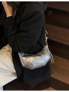 Silver metallic crescent dumpling shoulder bag with quilted texture on model outdoors