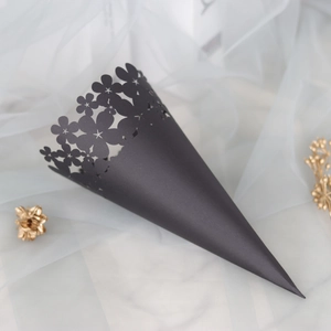 Close-up of black hollow-carved wedding confetti cone with floral laser-cut patterns