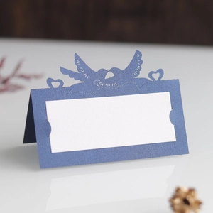 Detailed laser-cut blue table card featuring a hollow lovebird and heart pattern design