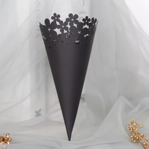 Close-up of black wedding confetti cone with laser-cut floral patterns and star details