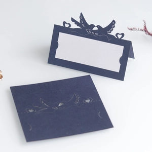 Detail of navy blue hollow bird design wedding place card with elegant laser-cut heart texture