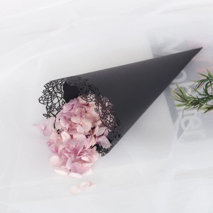 Close-up of black lace hollow paper cone filled with purple dried petals for weddings