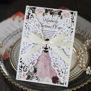 Detailed laser-cut wedding invitation featuring elegant floral patterns and a cream satin bow