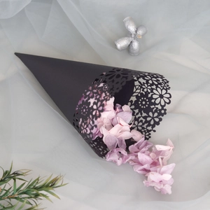 Detailed laser-cut black paper cone filled with pink flower petals for wedding decor