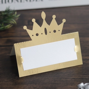 Macro shot of elegant gold hollow crown place card for weddings with a white name area