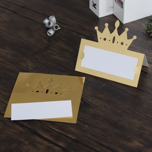 Macro shot of gold hollow crown place cards on a rustic wooden table for wedding decor