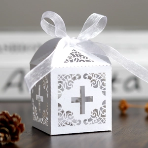 Detail of laser-cut cross pattern on white favor box with elegant satin ribbon bow