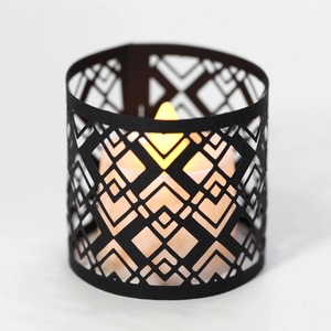 Macro shot of black hollow geometric paper lampshade with warm orange LED candle light