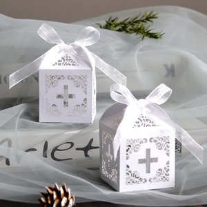 White laser-cut wedding favor box with cross design and silk ribbon on blue tulle
